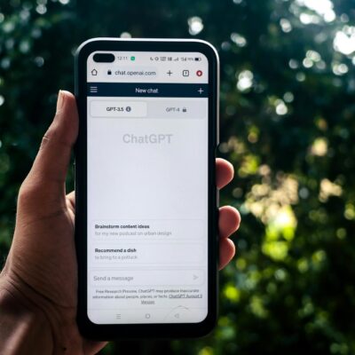 A person uses ChatGPT on a smartphone outdoors, showcasing technology in daily life.