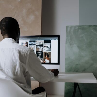 Back view of a man sitting at a computer, browsing images in a modern workspace.