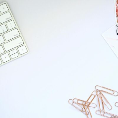 Clean and organized workspace featuring a keyboard and rose gold paper clips, perfect for design inspiration.