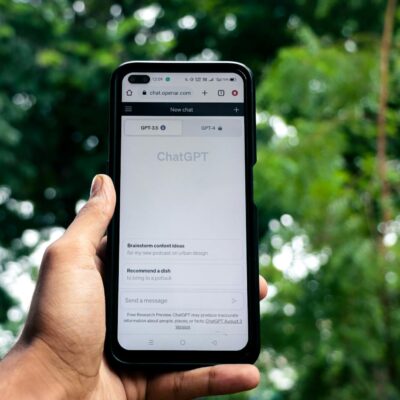 Close-up of a hand holding a smartphone displaying ChatGPT outdoors.