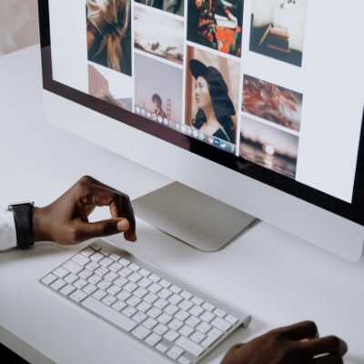 Man working on computer in modern office, viewing photography website. Clean and tech-focused environment.